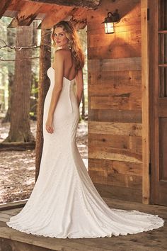 a woman in a white wedding dress standing on a porch with her back to the camera