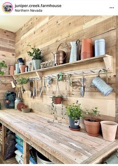 a wooden table topped with lots of pots and pans next to a shelf filled with potted plants