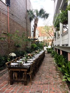 a long table set up outside with flowers and greenery