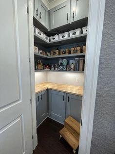 an open pantry with wooden counter tops and gray cabinets