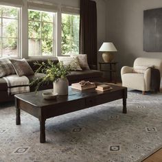 a living room with couches, chairs and a coffee table in front of a window