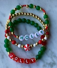 three bracelets with the word holly and candy cane charms on them sitting on a marble surface