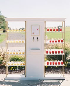 a white vending machine sitting on top of a cement ground next to a lush green field