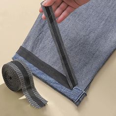 a person holding onto a piece of cloth with a tie on it and a roll of duct tape next to it