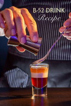 a person pouring liquid into a glass with a spoon in it and the words b - 52 drink recipe below