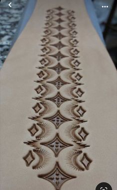 an embroidered table runner is shown in brown and beige colors, with intricate designs on the edge