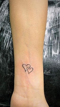 a small heart tattoo on the ankle with two smaller hearts in black ink, sitting on top of a woman's left foot