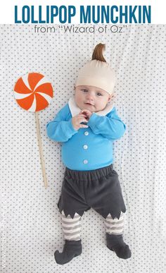 a baby laying on top of a bed next to a lollipop pin