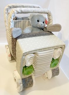 a teddy bear sitting in the back of a baby carriage made out of diapers