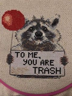 a raccoon holding a sign that says to me you are trash