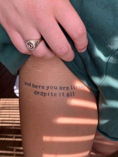 a person with a ring on their finger and some words on her leg that say, and here you are i will despite it all