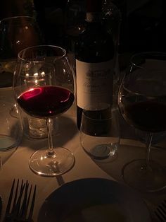 a table with wine glasses, plates and utensils sitting on top of it