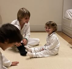 two young children sitting on the floor playing with their toys and smiling at each other