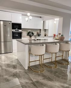 a kitchen with marble flooring and stainless steel appliances in the center, along with two bar stools