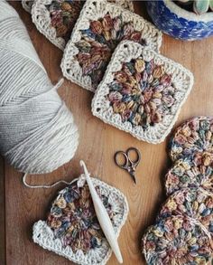 crocheted coasters with scissors and yarn on a wooden table next to balls of yarn