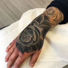 a hand with a black rose tattoo on it