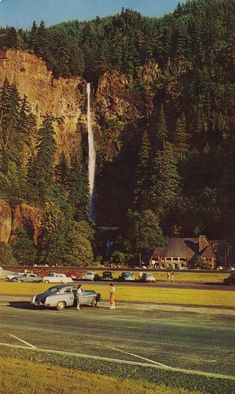 cars are parked in front of a waterfall