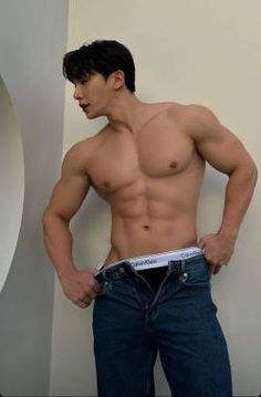 a shirtless man is standing in front of a wall with his hands on his hips