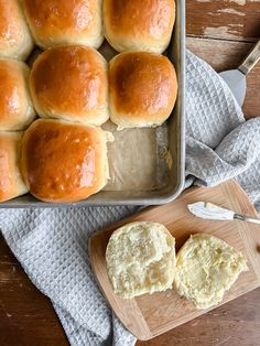 bread rolls in a baking pan with butter on the side next to a cutting board