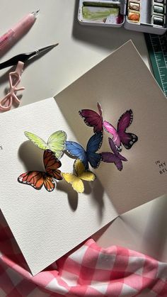 a card with three butterflies on it next to some scissors and other crafting supplies