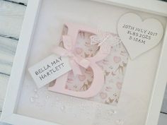 a baby's first birthday card in a white frame with a pink bow and name tag