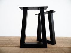 two black metal tables sitting on top of a wooden floor