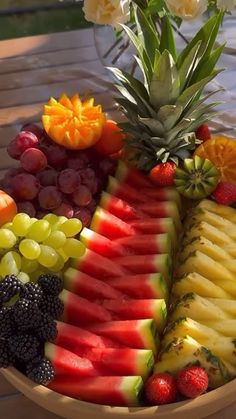 a wooden bowl filled with lots of different types of fruit on top of a table