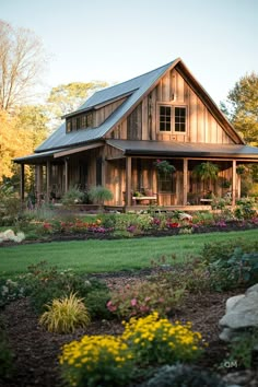 a large wooden house sitting on top of a lush green field next to flowers and trees