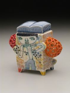 a ceramic object with an orange ball on it's side and a man in the middle