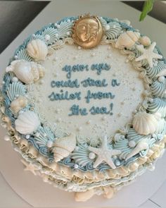 there is a cake that has shells on the bottom and writing on the side in blue frosting