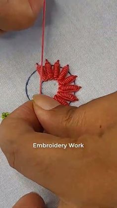 someone is doing something that looks like flowers on a piece of fabric with yarn in it