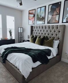 a large bed sitting in the middle of a bedroom with pictures on the wall above it