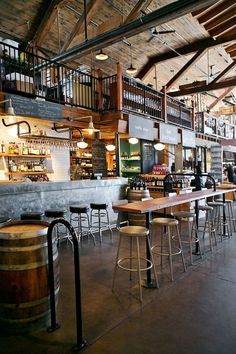 the inside of a bar with lots of stools and tables in front of it