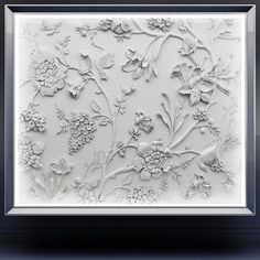 an intricately designed wall panel with flowers and leaves in white, framed on black frame