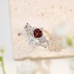 a close up of a ring with a red stone in the middle and white diamonds around it