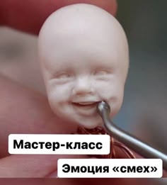 a baby doll being held up to the camera with a toothbrush in it's mouth