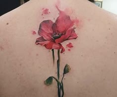 the back of a woman's shoulder with a watercolor flower tattoo on it