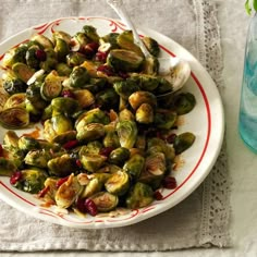 a white plate topped with brussel sprouts next to a glass of water