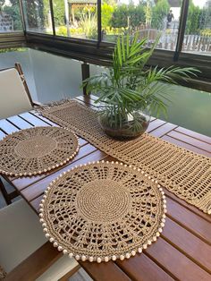 two crocheted placemats and a potted plant on a wooden table