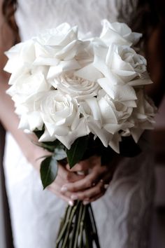 a bride holding a bouquet of white roses