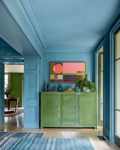 a living room with blue walls and green furniture in the center, along with an area rug on the floor