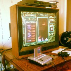 an old computer monitor sitting on top of a wooden table next to a game controller