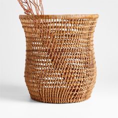 a woven basket with some branches sticking out of the top, on a white background