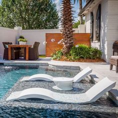 an outdoor swimming pool with lounge chairs and palm trees in the backround area