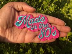 someone is holding out their pink and blue made in the 90's patch