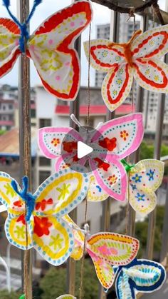 colorful paper butterflies hanging from the side of a pole in front of a cityscape