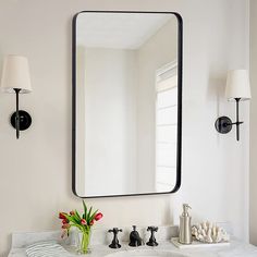 a bathroom sink with a mirror above it and a vase on the counter next to it