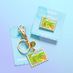 two keychains with stamps on them are sitting next to each other in front of a blue background