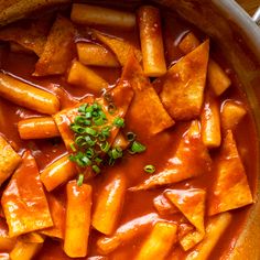 a pot filled with lots of food and garnished in sauce on top of a wooden table