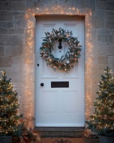 a white door decorated with christmas lights and wreath